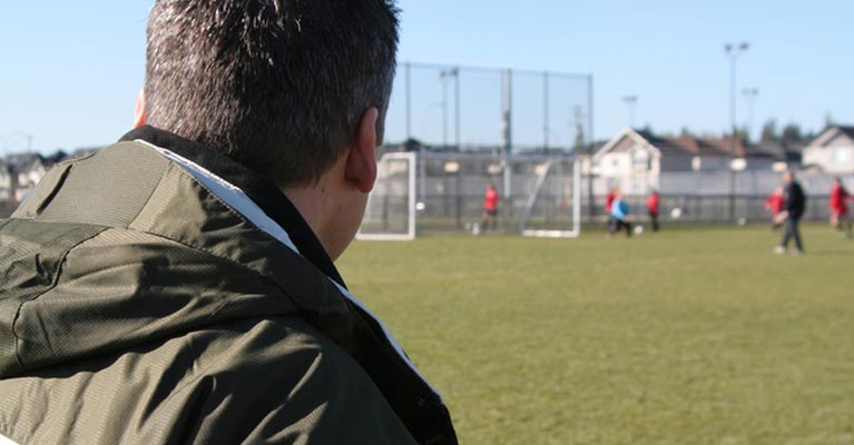 Soccer parent watching his kids playing football